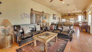 A spacious living room with leather sofas, a wooden coffee table, and a ceiling fan. - 'the Hideaway' - Santa Fe-style Home in Rio Verde! (Rio Verde)