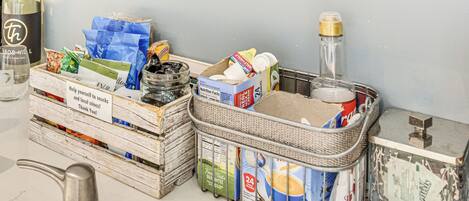 A kitchen counter with various food items, a bottle of wine, and a metal pitcher.