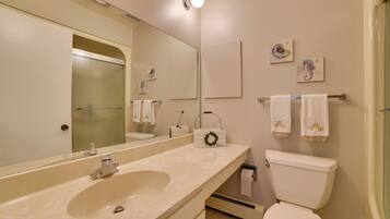 A bathroom with a large mirror, a sink, a toilet, and towels on a rack.