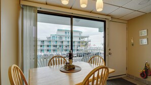 Hotellihuone, jossa on puinen ruokapöytä, neljä tuolia, suuri ikkuna, josta on näkymä rakennukseen, ja parveke.