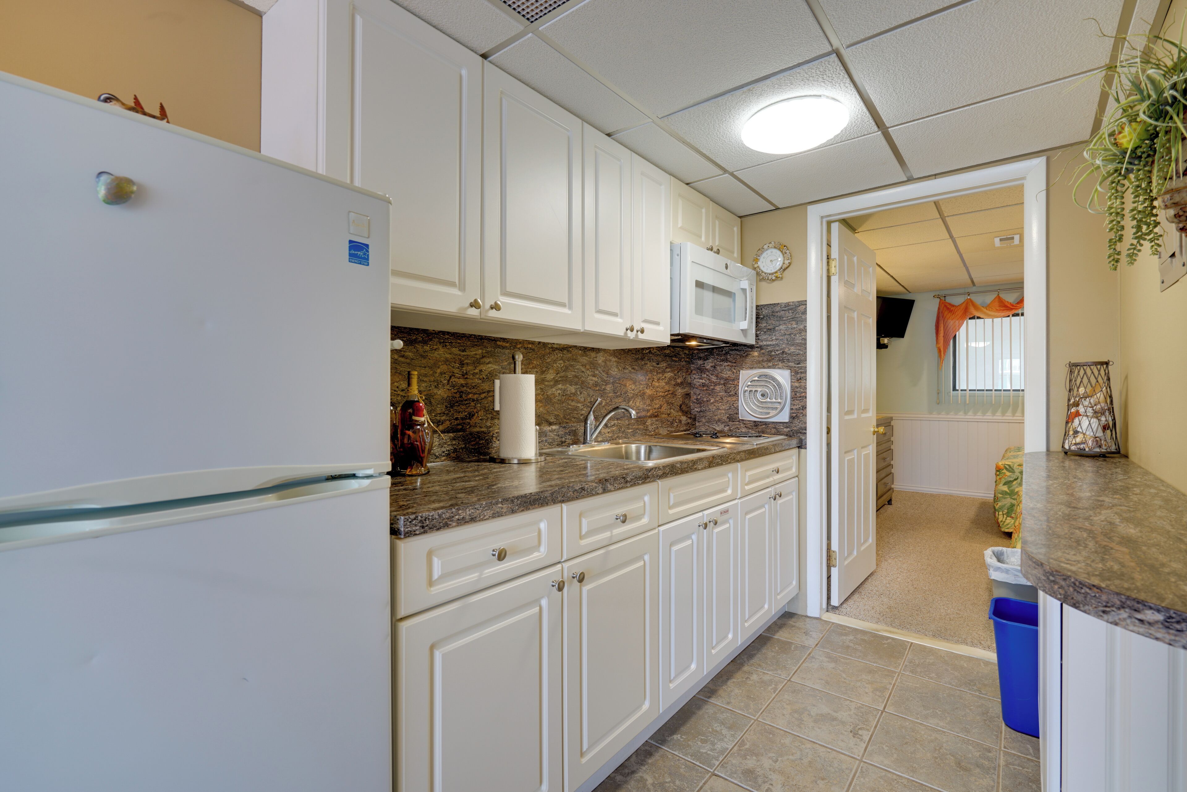 A kitchen with white cabinets, a microwave, and a refrigerator.