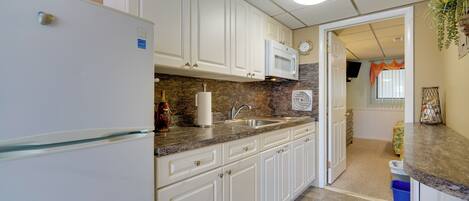 A kitchen with white cabinets, a microwave, and a refrigerator.