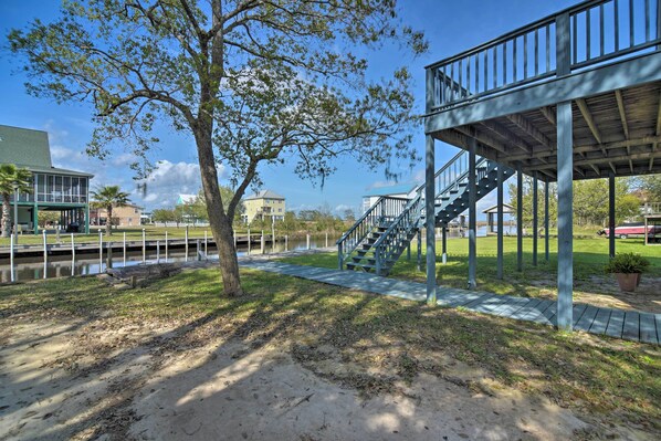 A park with a wooden deck, a staircase, and a pathway leading to a water body. - Fish at Canalfront Bay St Louis Home - Dock & Deck (Bay St Louis)