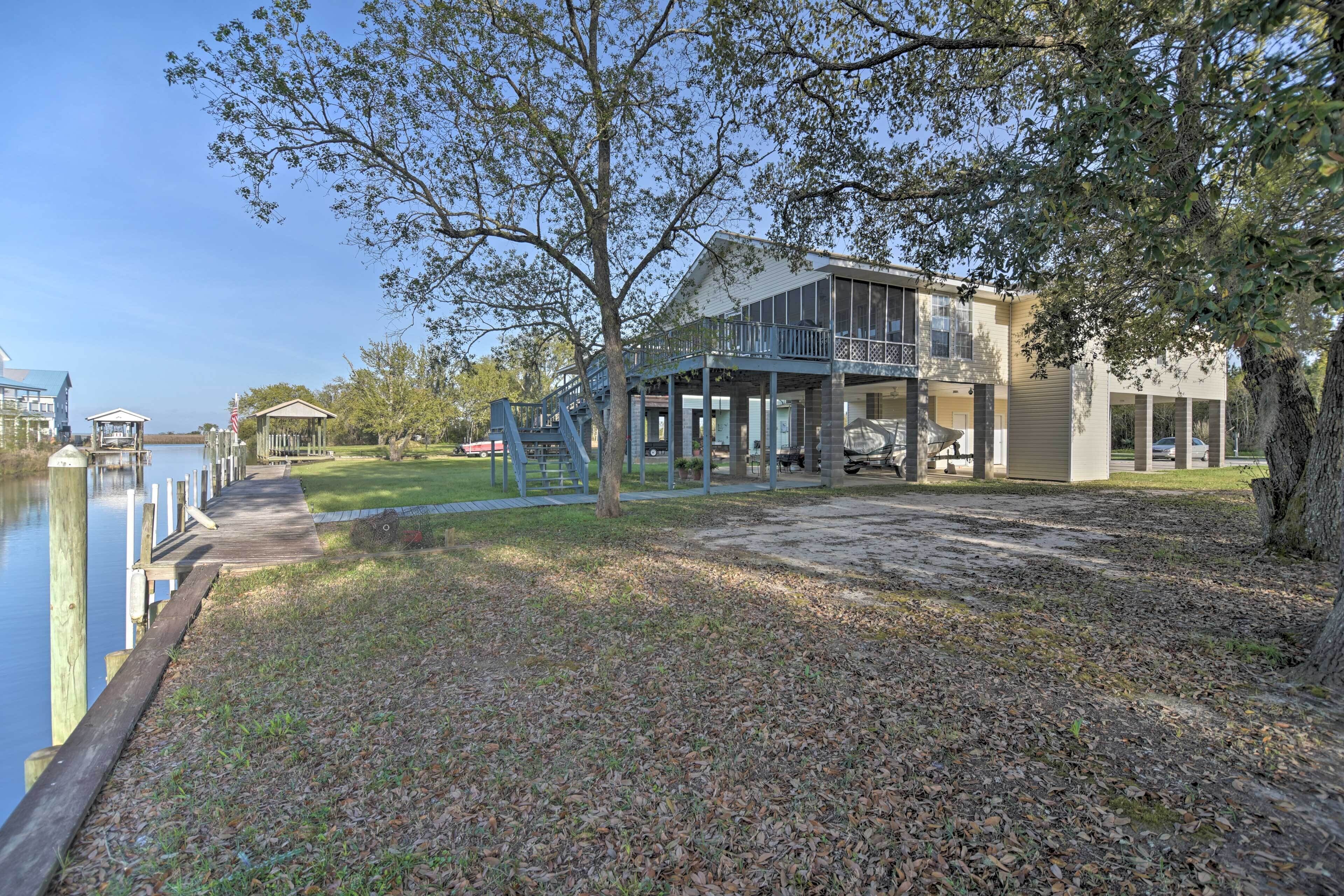 A waterfront property with a dock, a covered patio, and a large house with a balcony.