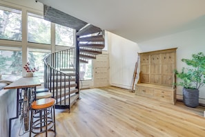 Ein geräumiges Zimmer mit Wendeltreppe, Holzboden, einem Holzschrank und einem Blumentopf.