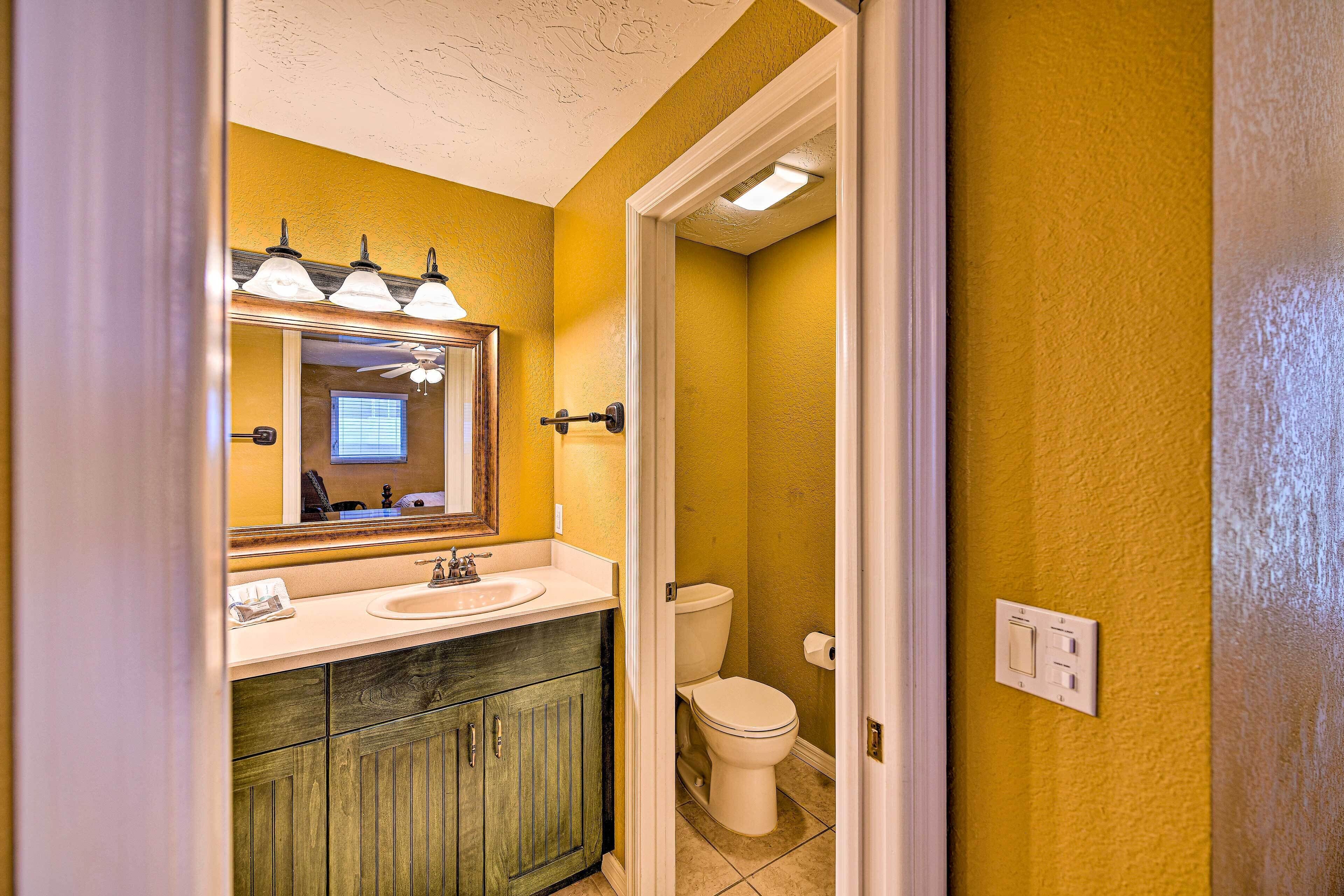 Une salle de bain avec un mur jaune, un lavabo blanc et un meuble en bois.