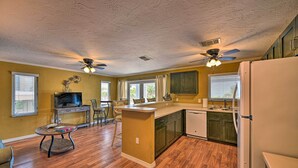 A spacious kitchen with wooden flooring, a central island, and a ceiling fan.