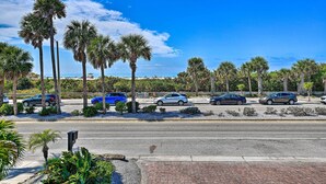 A parking lot with several cars, palm trees, and a clear blue sky.