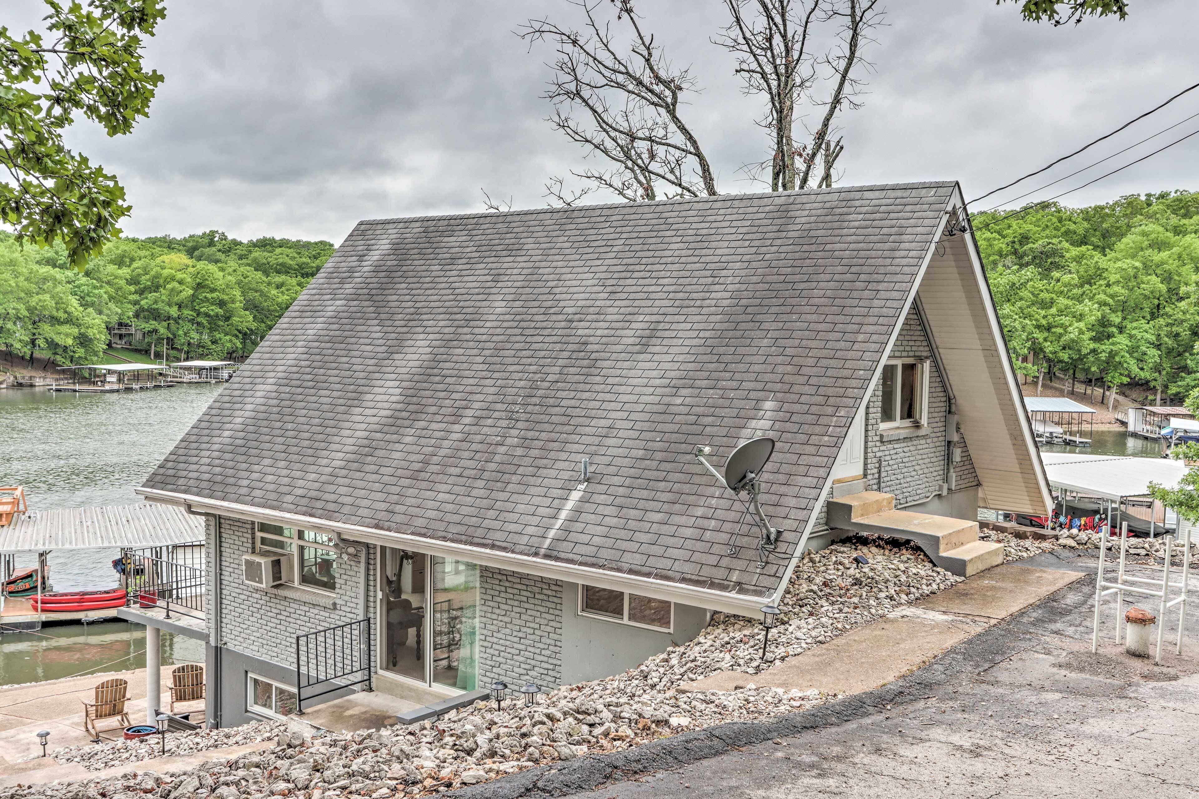 Une maison avec un toit en pente, une antenne parabolique et un quai avec un bateau.
