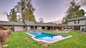 A backyard with a swimming pool, outdoor seating, and a covered patio area.
