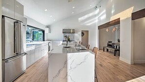 A modern kitchen with a large island, stainless steel appliances, and a view to the outdoors.