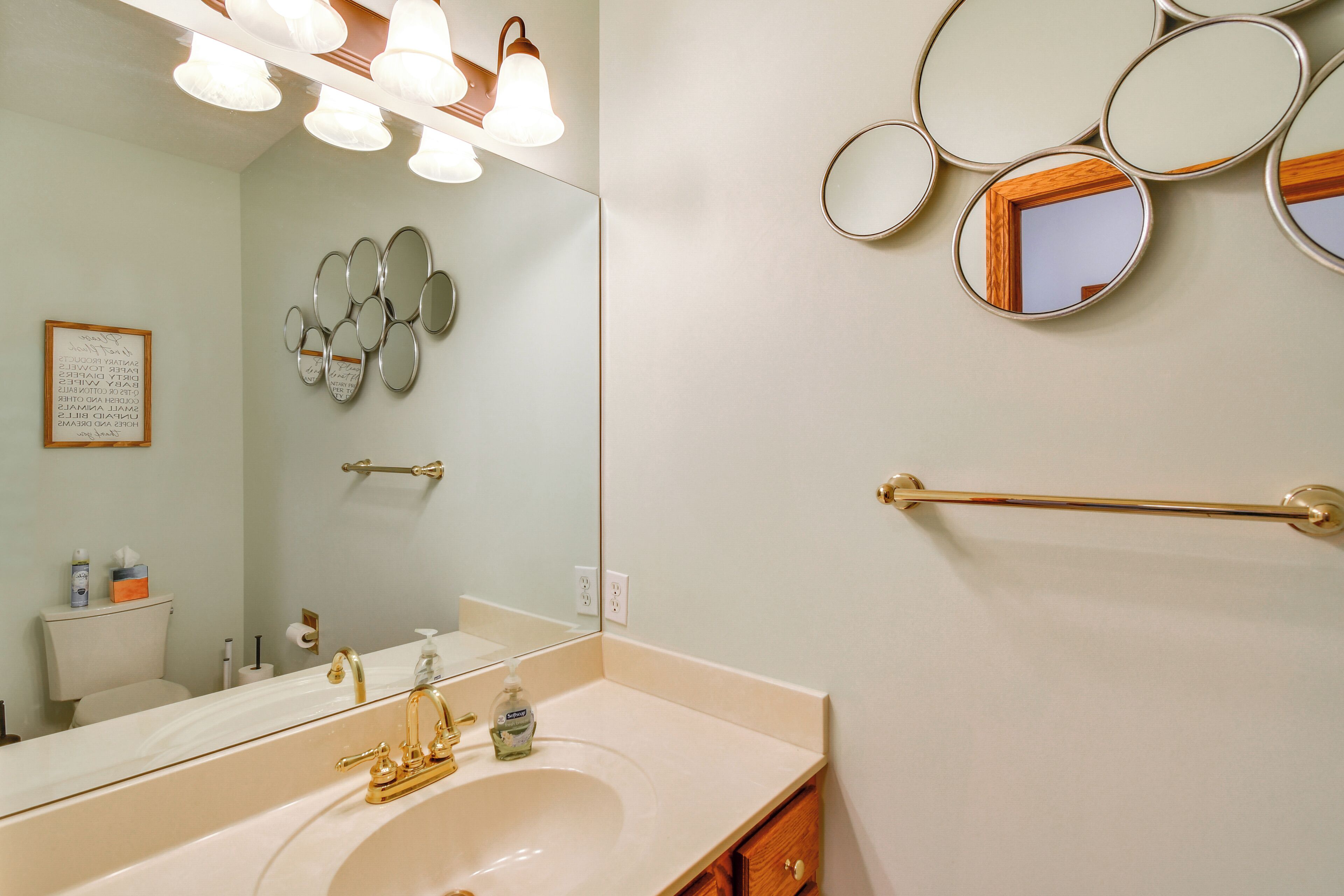 A bathroom with a large mirror, multiple smaller mirrors, a gold faucet, and a towel rack.