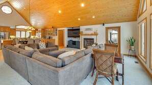 Een ruime woonkamer met een grote hoekbank, een eettafel met stoelen en een open haard.