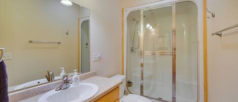 Un baño con lavamanos doble, inodoro y ducha con mampara de vidrio.
