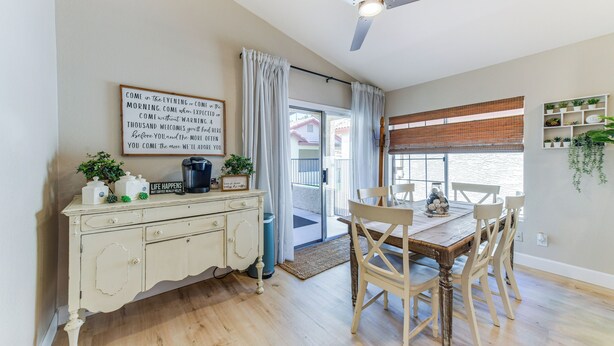 A dining area with a wooden table and chairs, a ceiling fan, and a view of the outside through a window with curtains. - Updated Gilbert Home w/ Covered Patio (Gilbert)
