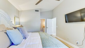 A bedroom with a bed, a ceiling fan, a TV mounted on the wall, and a door leading to another room. - Updated Gilbert Home w/ Covered Patio (Gilbert)
