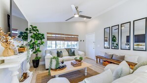 A modern living room with a sofa, coffee table, and potted plants. - Updated Gilbert Home w/ Covered Patio (Gilbert)