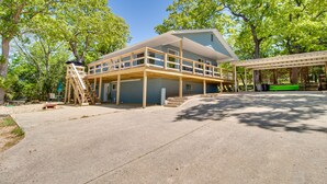 Ein zweistöckiges Haus mit Balkon, einer Holzterrasse und einem überdachten Außenbereich.