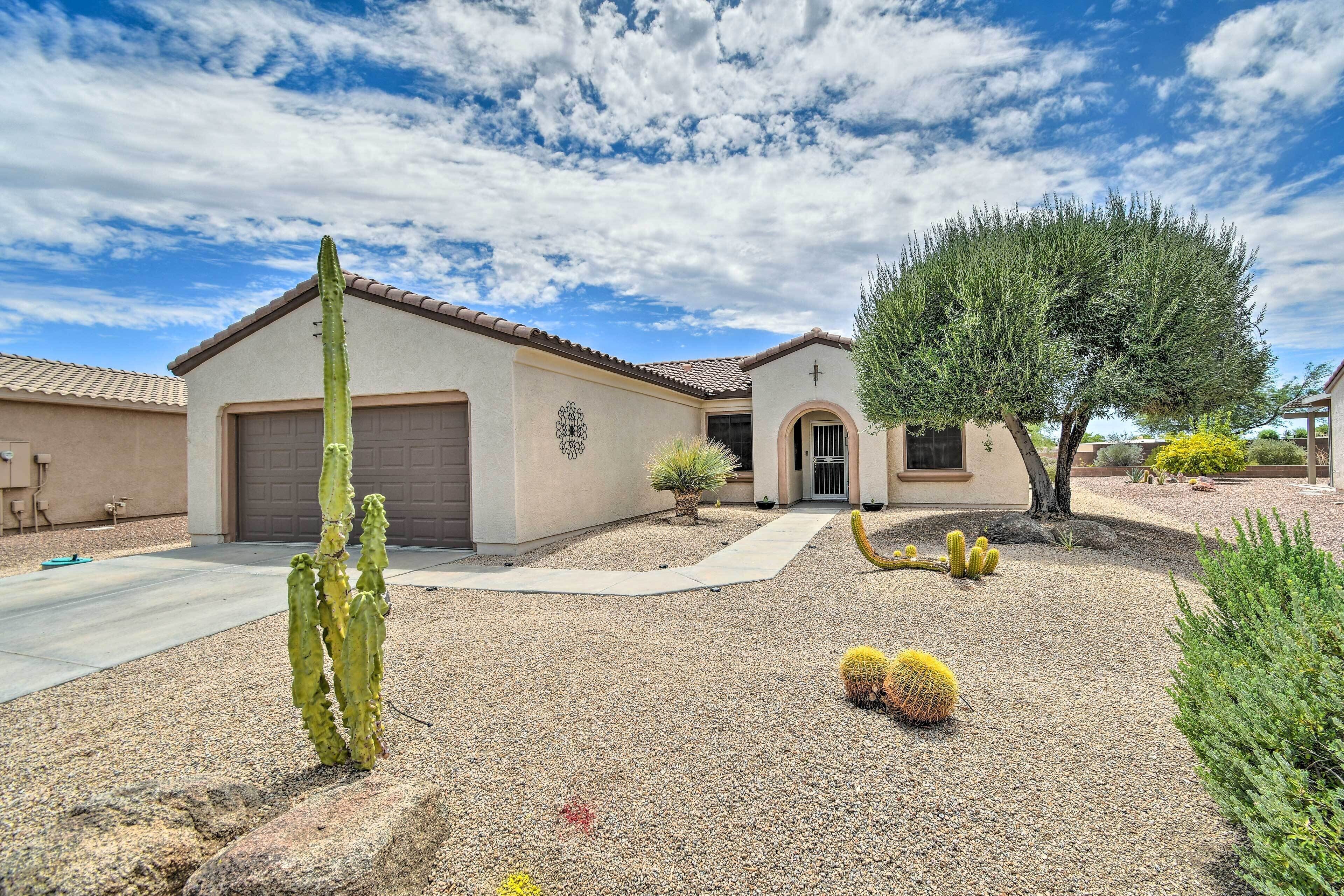 A residential property with a single-story house, a driveway, and a well-maintained garden with cacti and a tree.