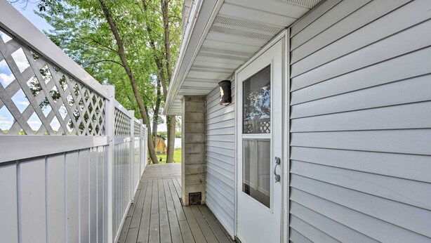 A covered wooden deck with a white fence and a concrete pillar. - Sunrise Bay w/ Lake Access: Families Welcome! (Isanti)