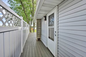 A covered wooden deck with a white fence and a concrete pillar.