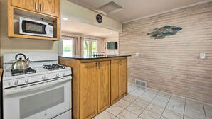 A kitchen with wooden cabinets, a microwave, a stove, and a tiled floor. - Sunrise Bay w/ Lake Access: Families Welcome! (Isanti)