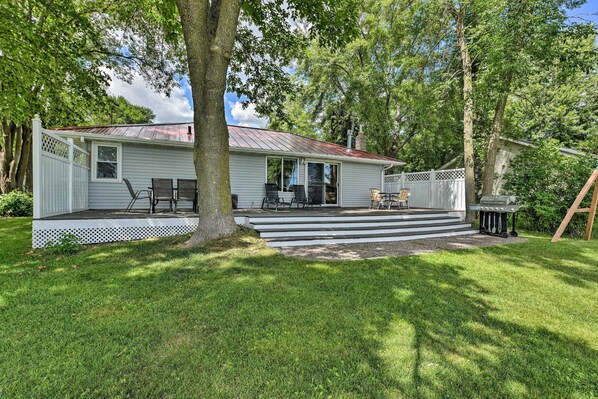 A single-story house with a covered patio, a lawn, and a wooden deck.