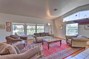 A spacious living room with multiple seating options, large windows, and a red patterned rug. - Wraparound Balcony & Mtn Views: Home in Sedona (Sedona)