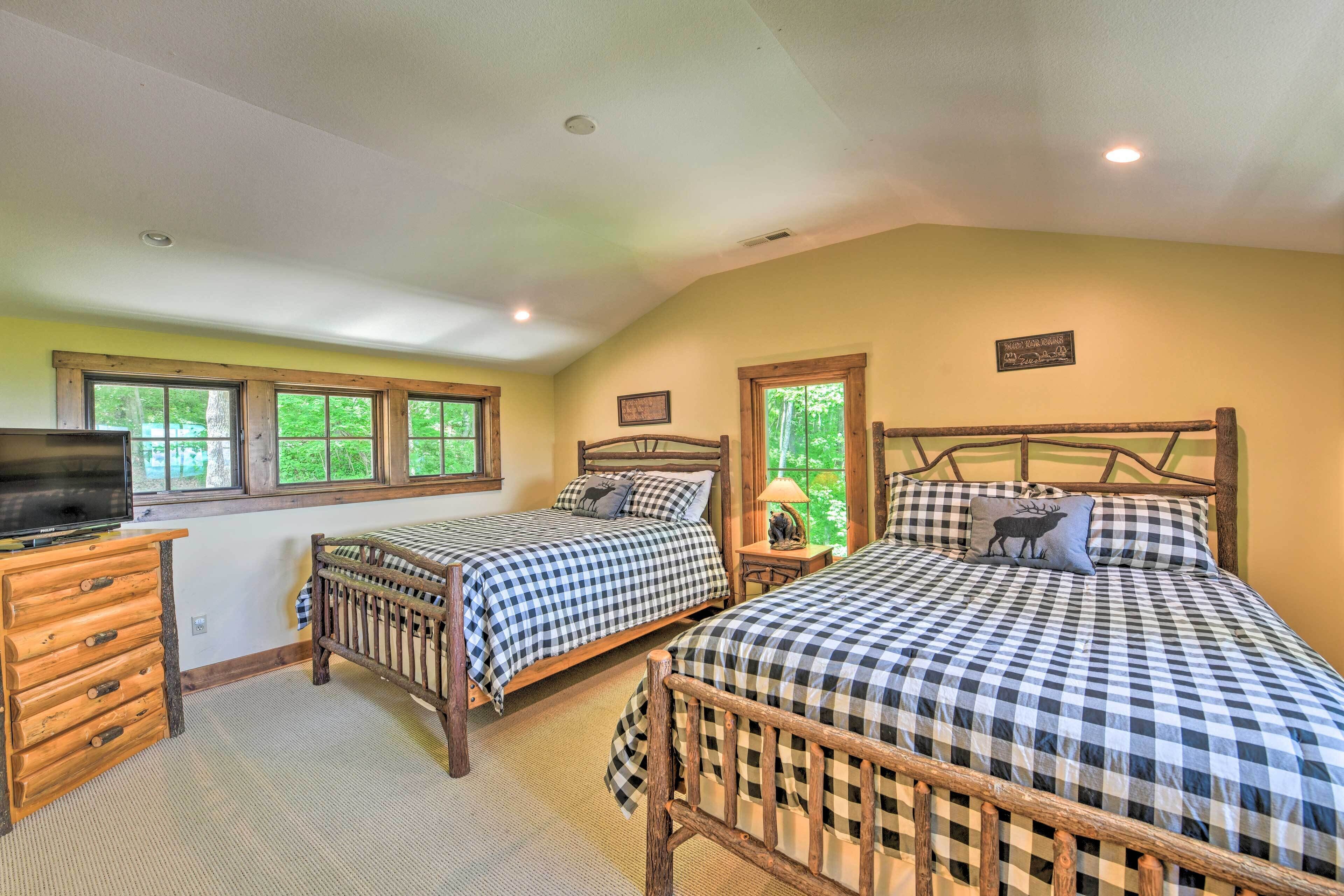 A room with two beds, a wooden dresser, and a television.