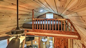 An attic bedroom with a wooden ceiling, a bed, a small window, and a ceiling fan. - 'the Gosling' Studio Cabin w/ River Access! (New Bern)