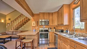 A kitchen with wooden cabinets, a stainless steel oven, a microwave, and a large window. - Townhome w/ Club Access on Shuttle Stop (Fraser)