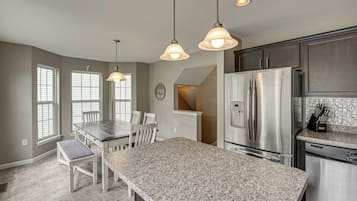 A kitchen with a granite countertop, stainless steel appliances, and pendant lighting.