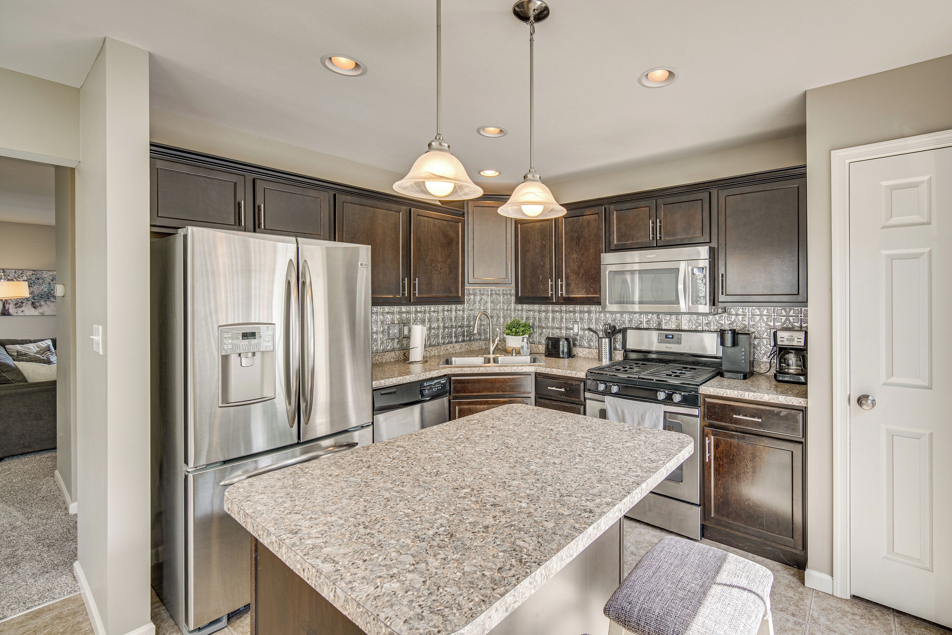 A modern kitchen with stainless steel appliances, granite countertops, and dark wood cabinets.