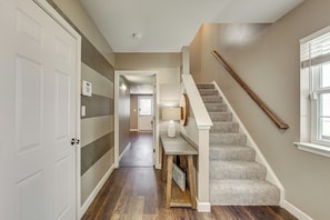 A hallway with a carpeted staircase, a door, and a wall-mounted intercom. - Charming Bellefonte Townhome Near Penn State! (Bellefonte)