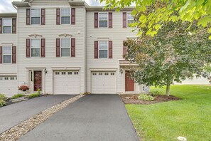 A multi-story residential building with a driveway, garage, and a well-maintained lawn.