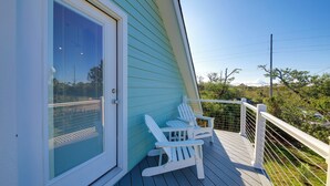 Una terrazza con due poltrone Adirondack bianche, un parapetto bianco e una vista libera sul cielo e sul verde circostante.