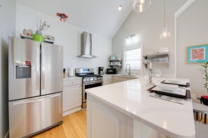 A modern kitchen with stainless steel appliances, a central island, and a dining area with a white countertop.