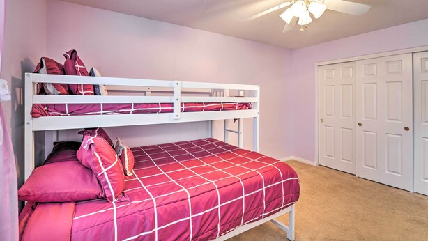 A bunk bed with a red and white checkered bedspread, a ceiling fan, and a white door in a room with light pink walls. - ~3,900 Sq Ft North Vegas Escape w/ RV Parking! (North Las Vegas)