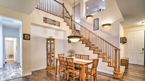 A spacious dining area with a wooden table and chairs, a staircase with wooden railings, and a hanging light fixture. - ~3,900 Sq Ft North Vegas Escape w/ RV Parking! (North Las Vegas)