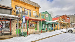 A snow-covered street with colorful buildings, including a restaurant and a pizza place.