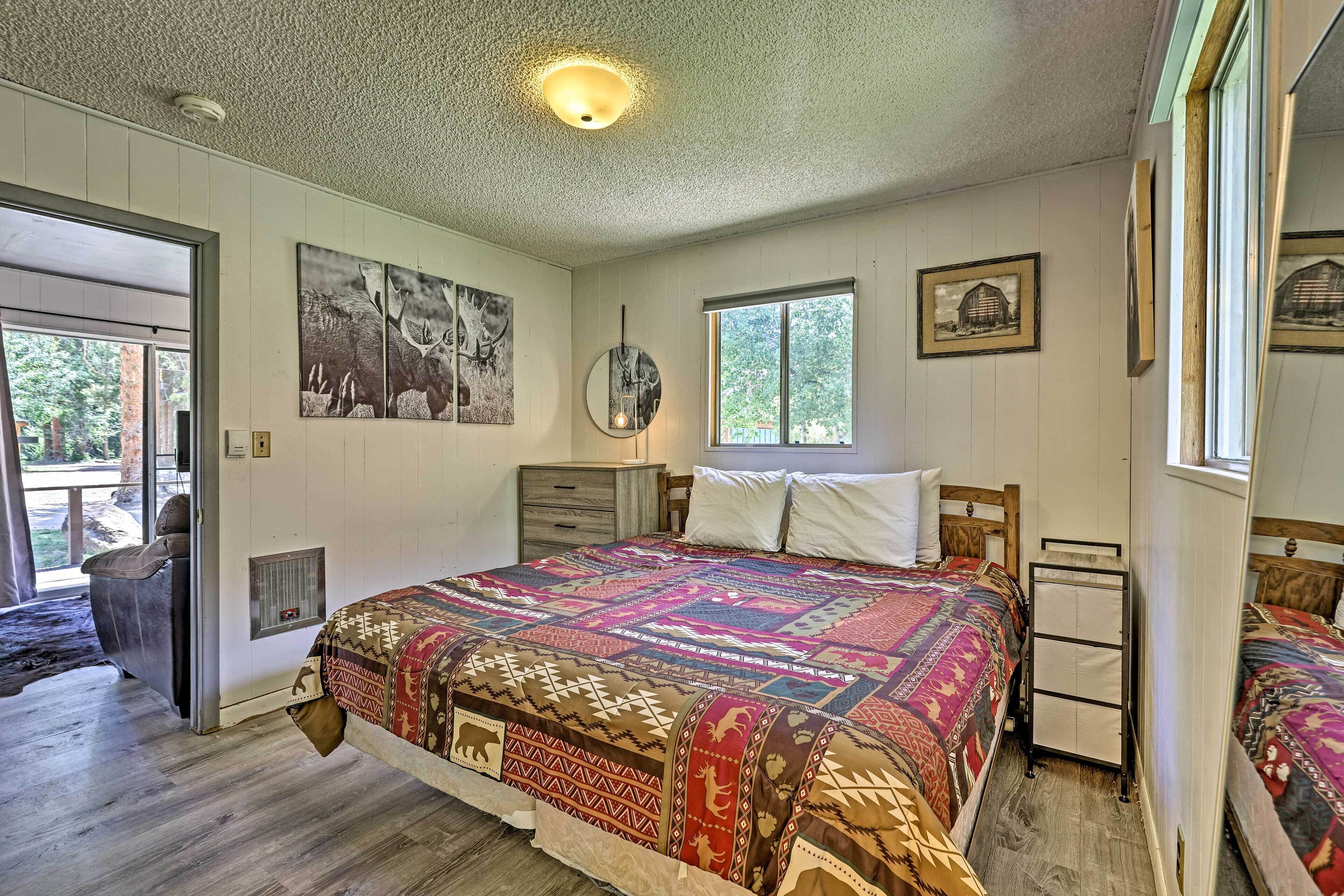 A bedroom with a large bed, a dresser, a mirror, and framed pictures on the wall.
