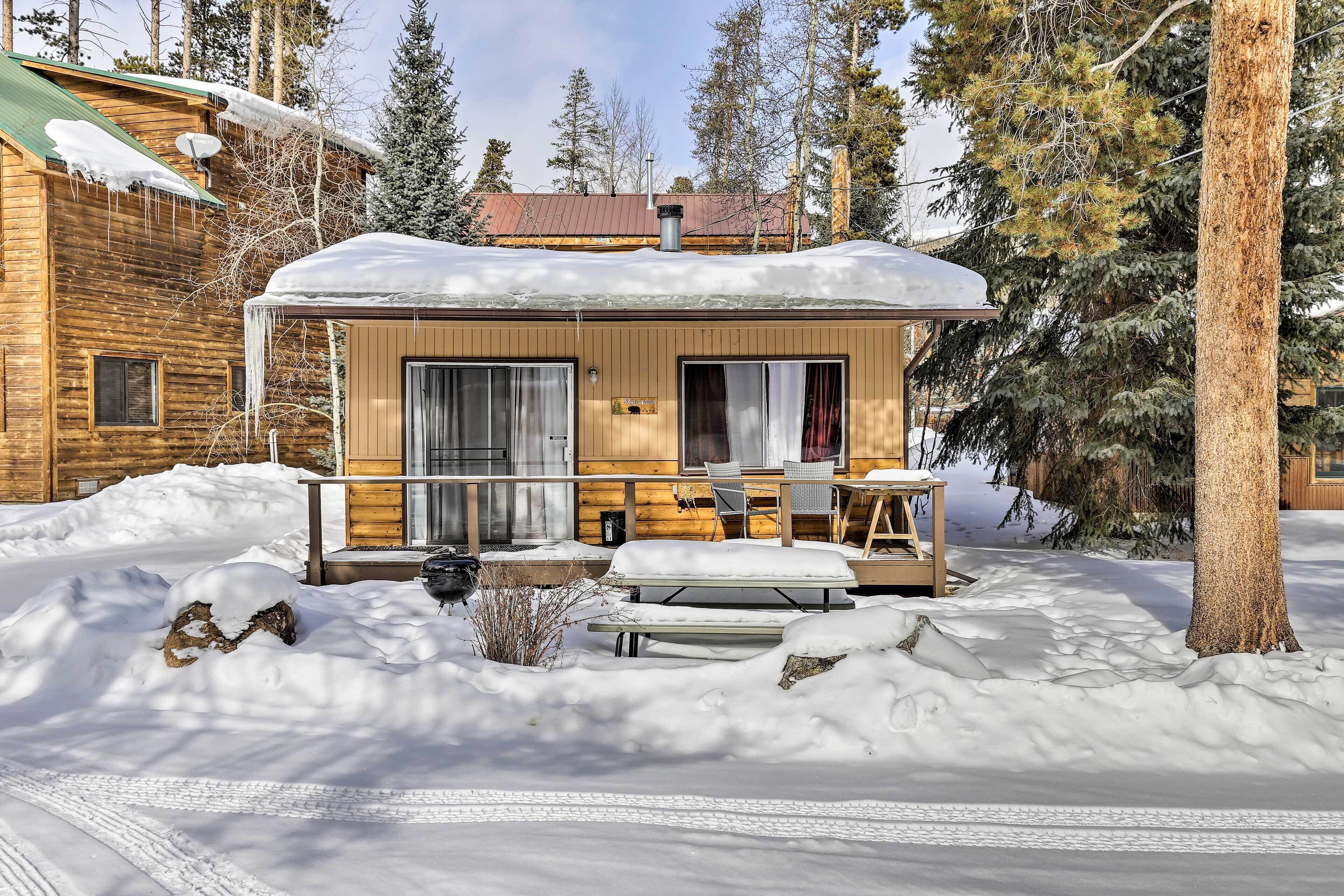 Une cabane en rondins avec un porche couvert, une petite table et un banc.