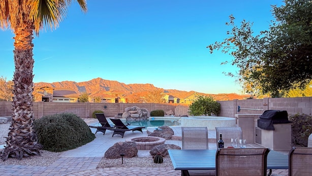 Un jardin avec une piscine, un espace détente et une vue sur les montagnes.