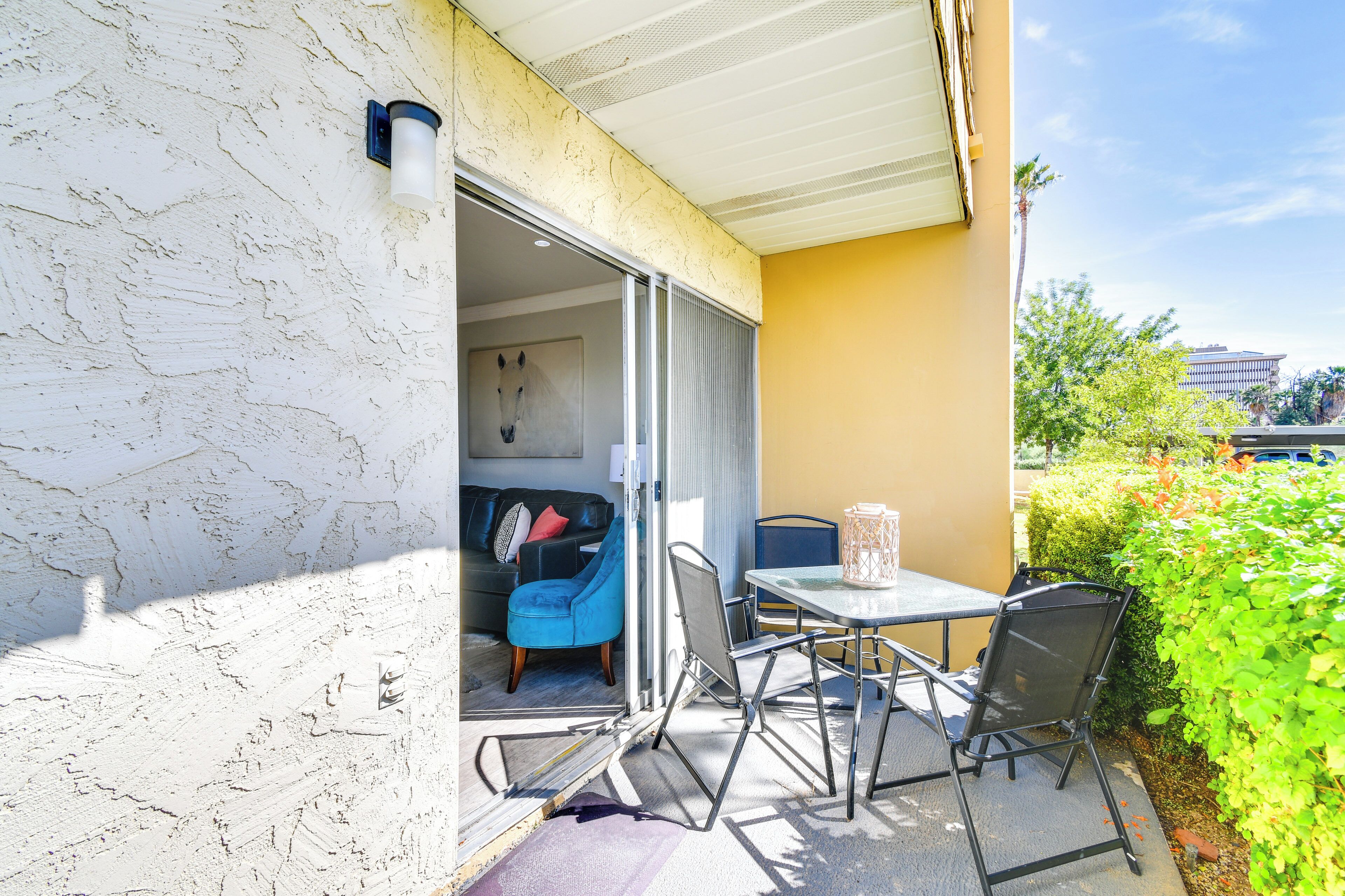 Una porta scorrevole aperta conduce a una stanza con una sedia blu, un tavolo e un bicchiere d'acqua.