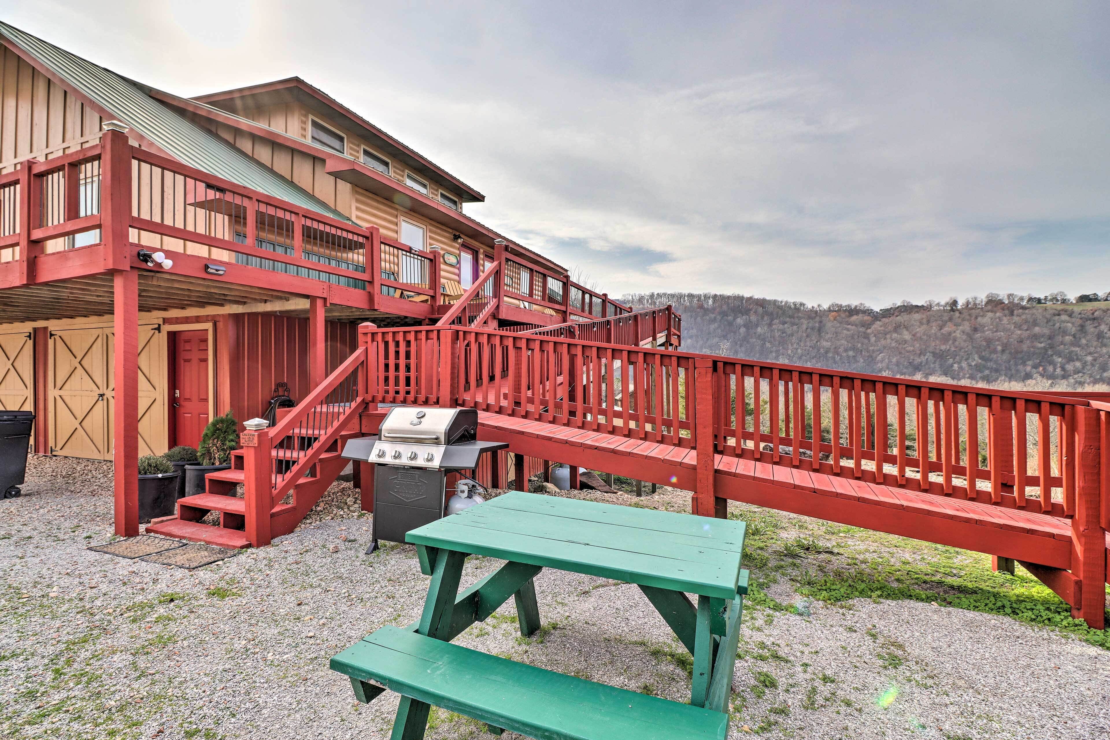 A rustic wooden building with a red exterior, a covered porch, and a picnic table.