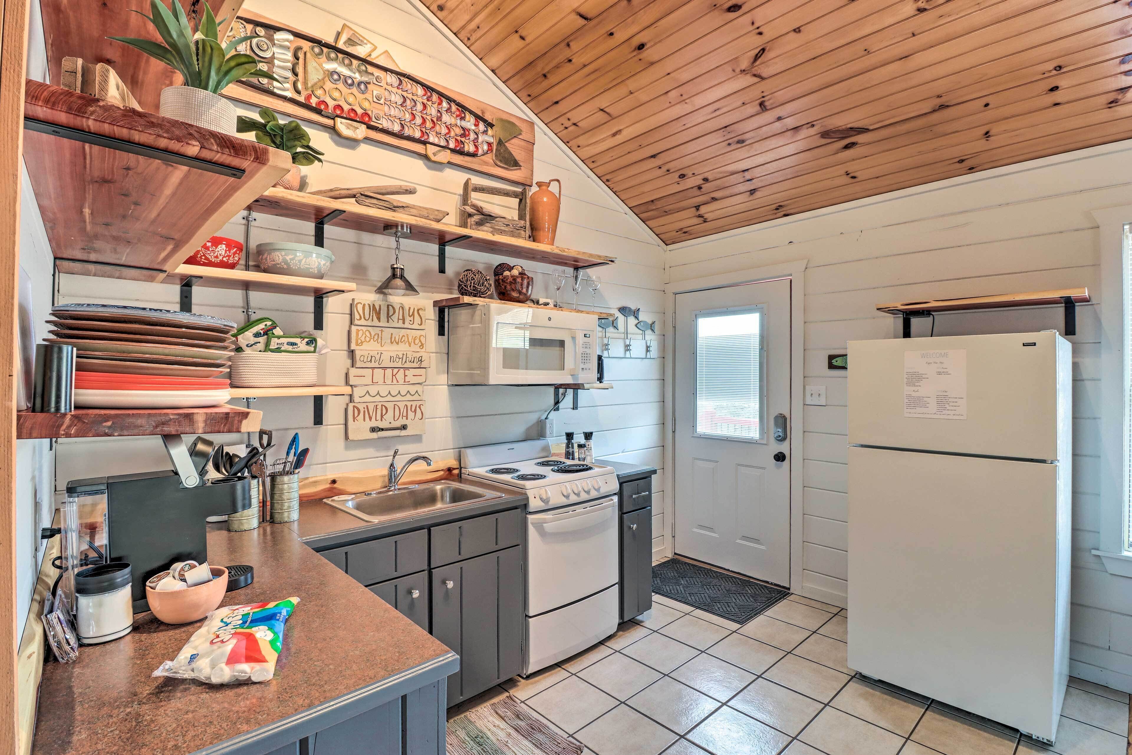 A kitchen with wooden shelves, a stove, a refrigerator, and a microwave.