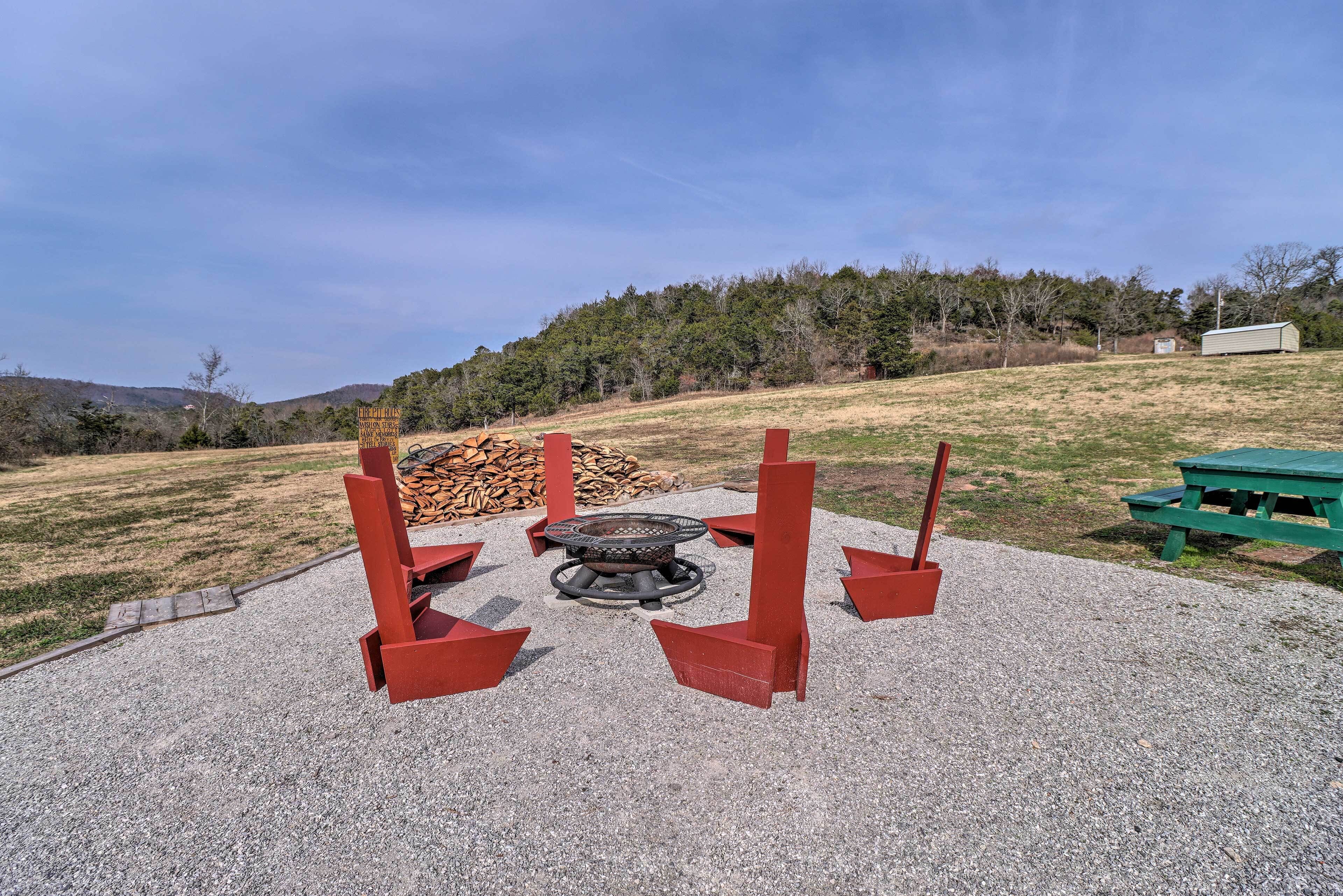 A fire pit with red stands in a gravel area with a picnic table and a shed in the background.