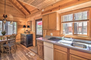 Interior de una cabaña de madera con una cocina que incluye armarios de madera, un lavavajillas y un fregadero.