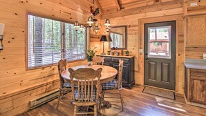 A wooden cabin interior with a dining table, chairs, a chandelier, and a kitchen area. - Pinetop-lakeside Cabin w/ Deck: Hike, Ski & Golf (Pinetop)