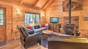 A cozy cabin interior with a wooden interior, a sofa, a television, and a fireplace. - Pinetop-lakeside Cabin w/ Deck: Hike, Ski & Golf (Pinetop)